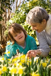 A girl with Down syndrome and her grandmother in a garden.